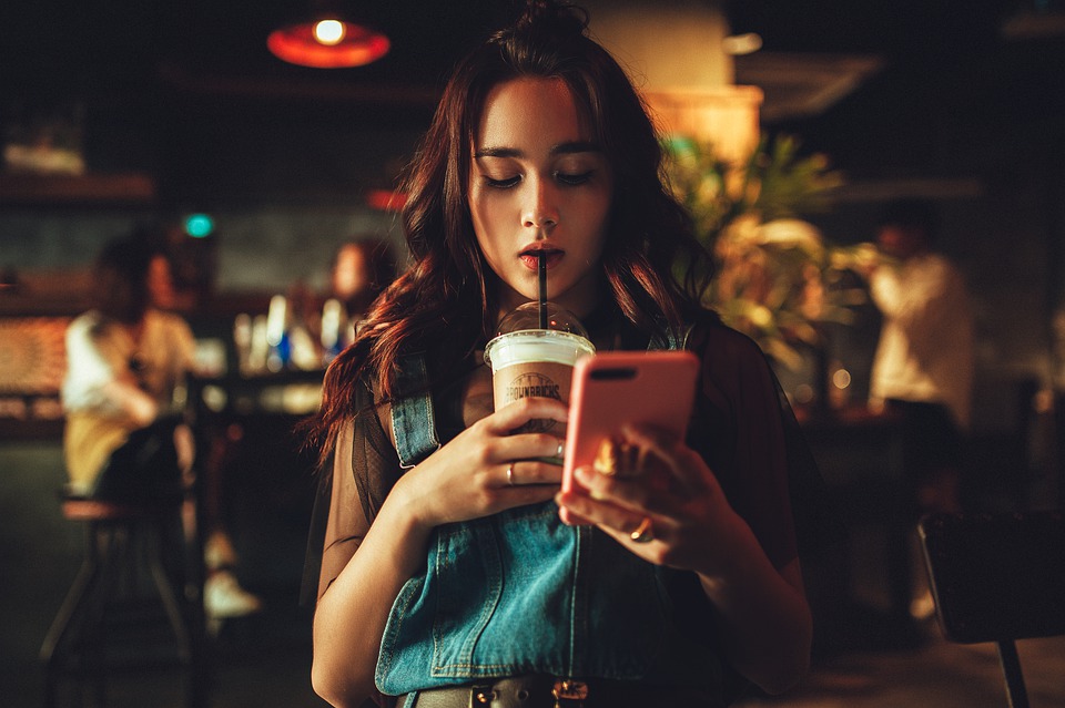 woman drinking and using her phone